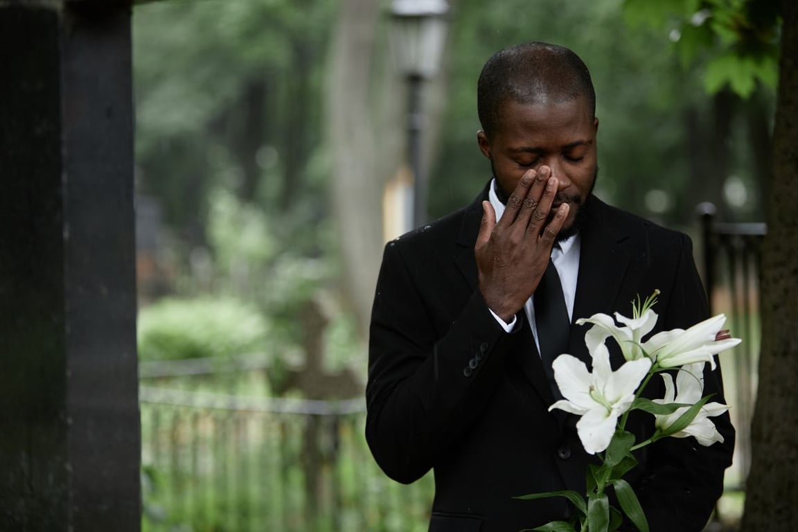 a man wearing a blacksuit while holding flowers