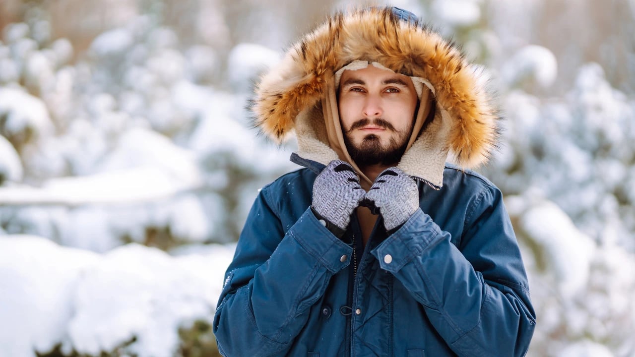 a man holding his jacket in the snow