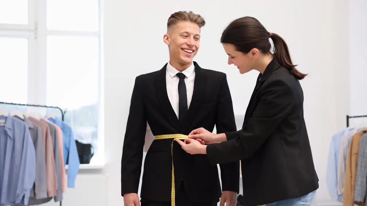 a women measuring the jacket waist of a man
