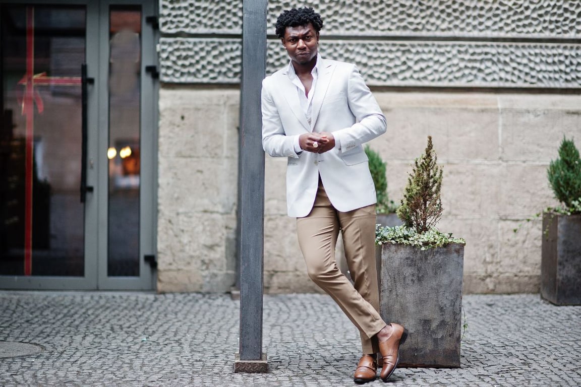 a man leaning on the post while wearing Spring clothes