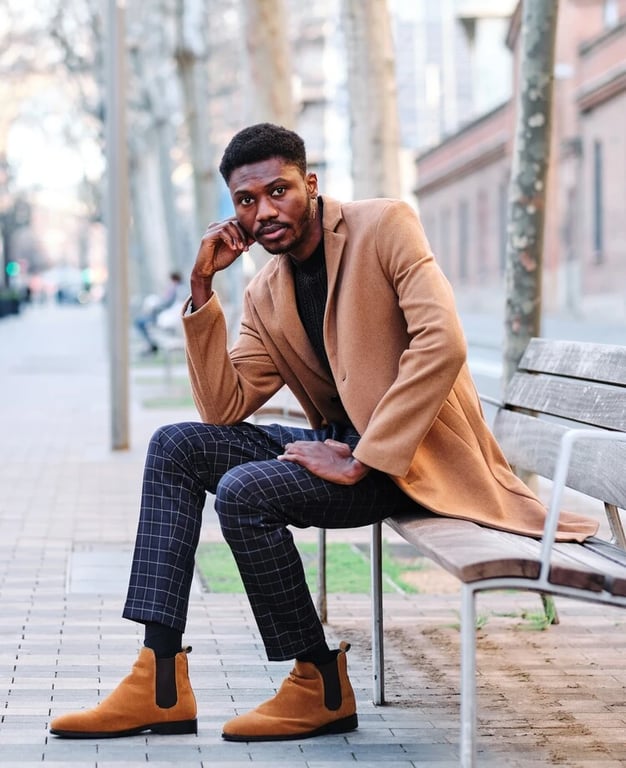 black man on chelsea boot sitting on a bench outdoors