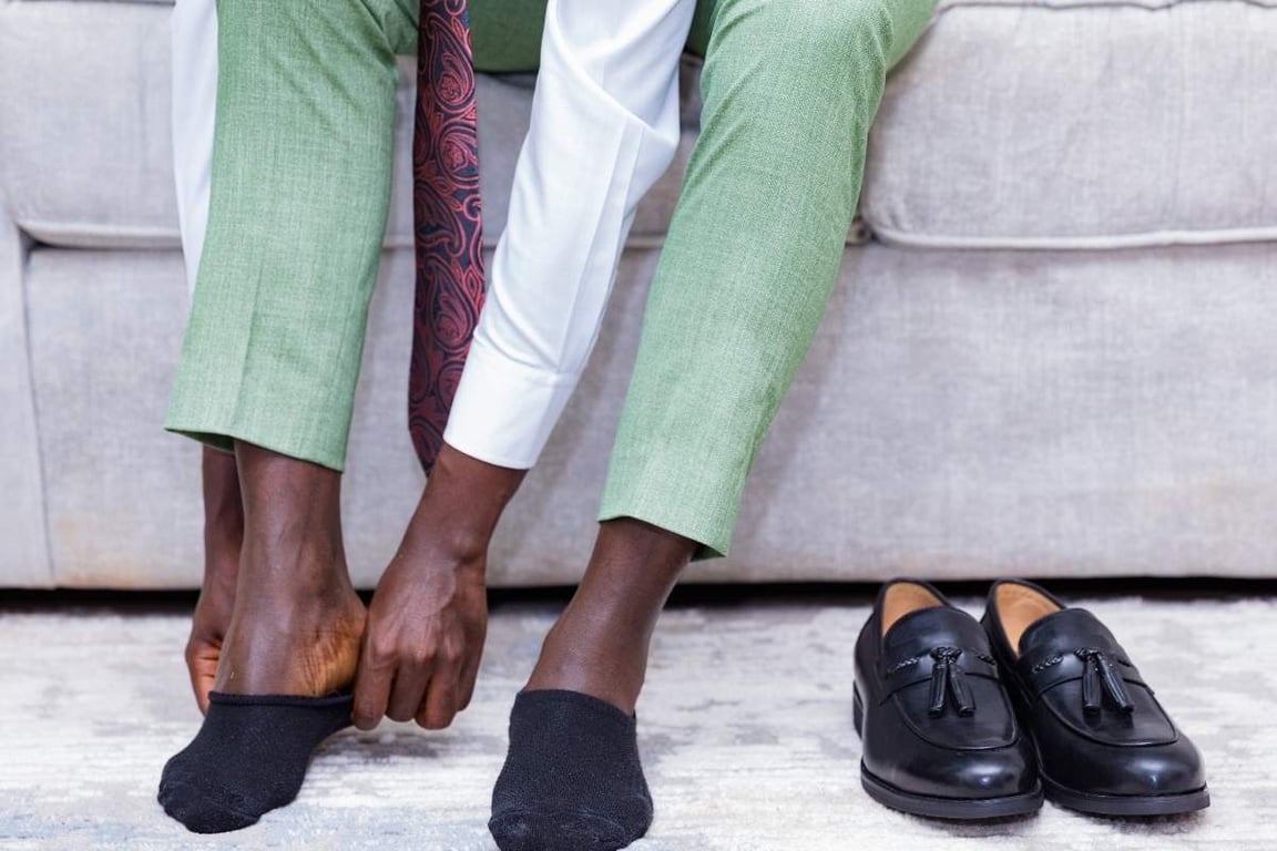 a person putting on socks for his loafer shoes